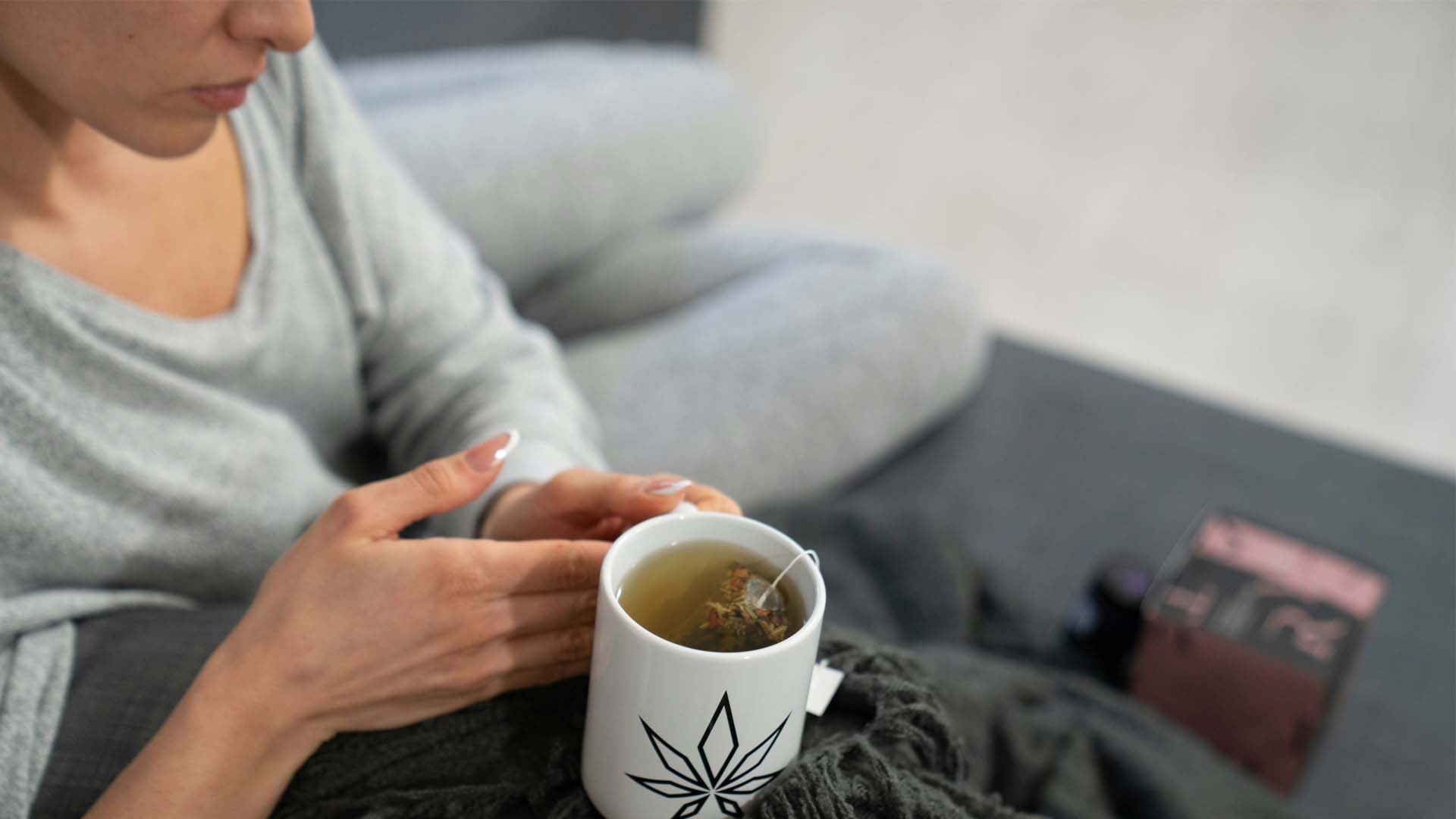Woman enjoying cannabis tea sitting on a couch