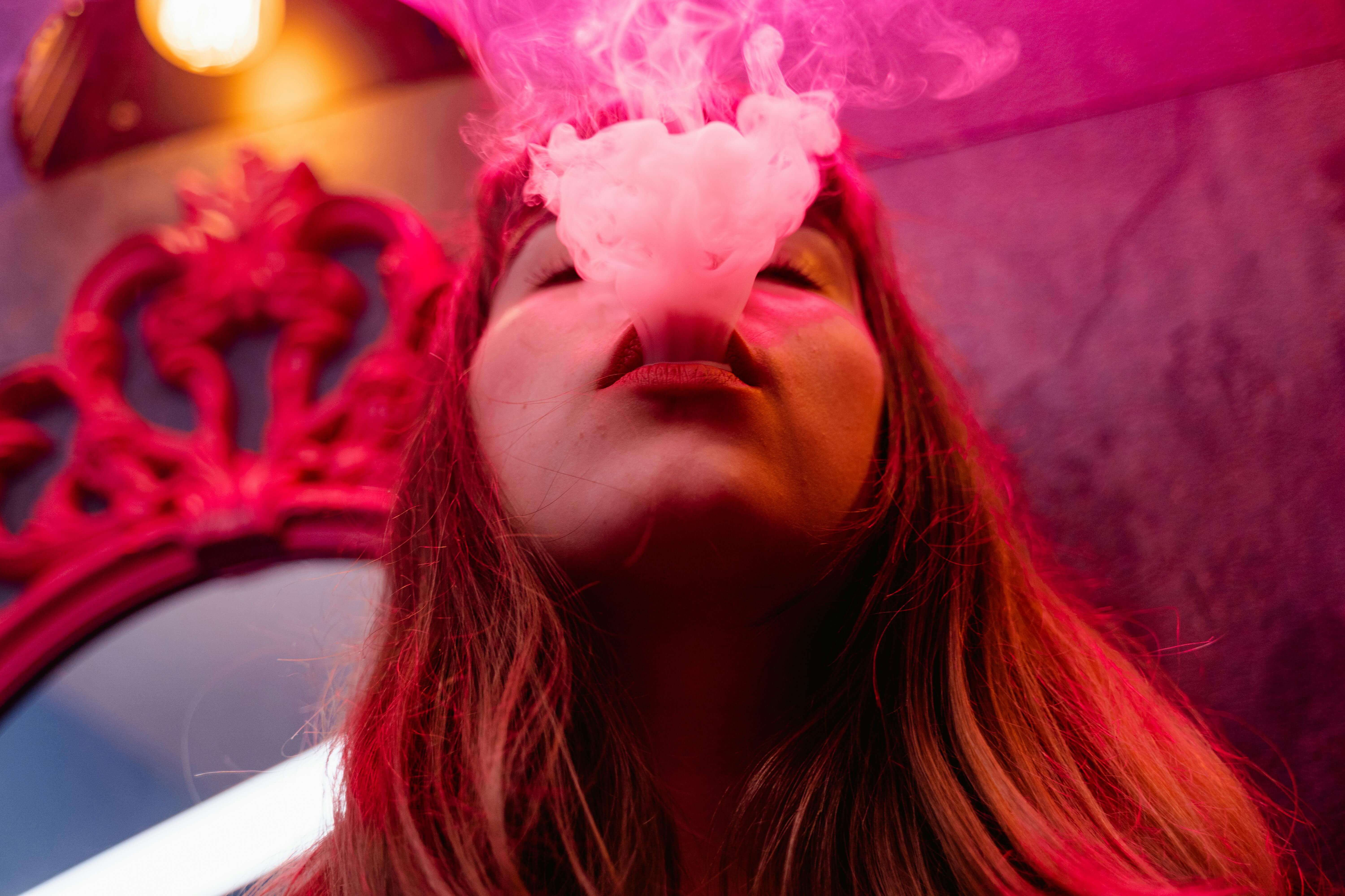 A young woman blowing out smoke