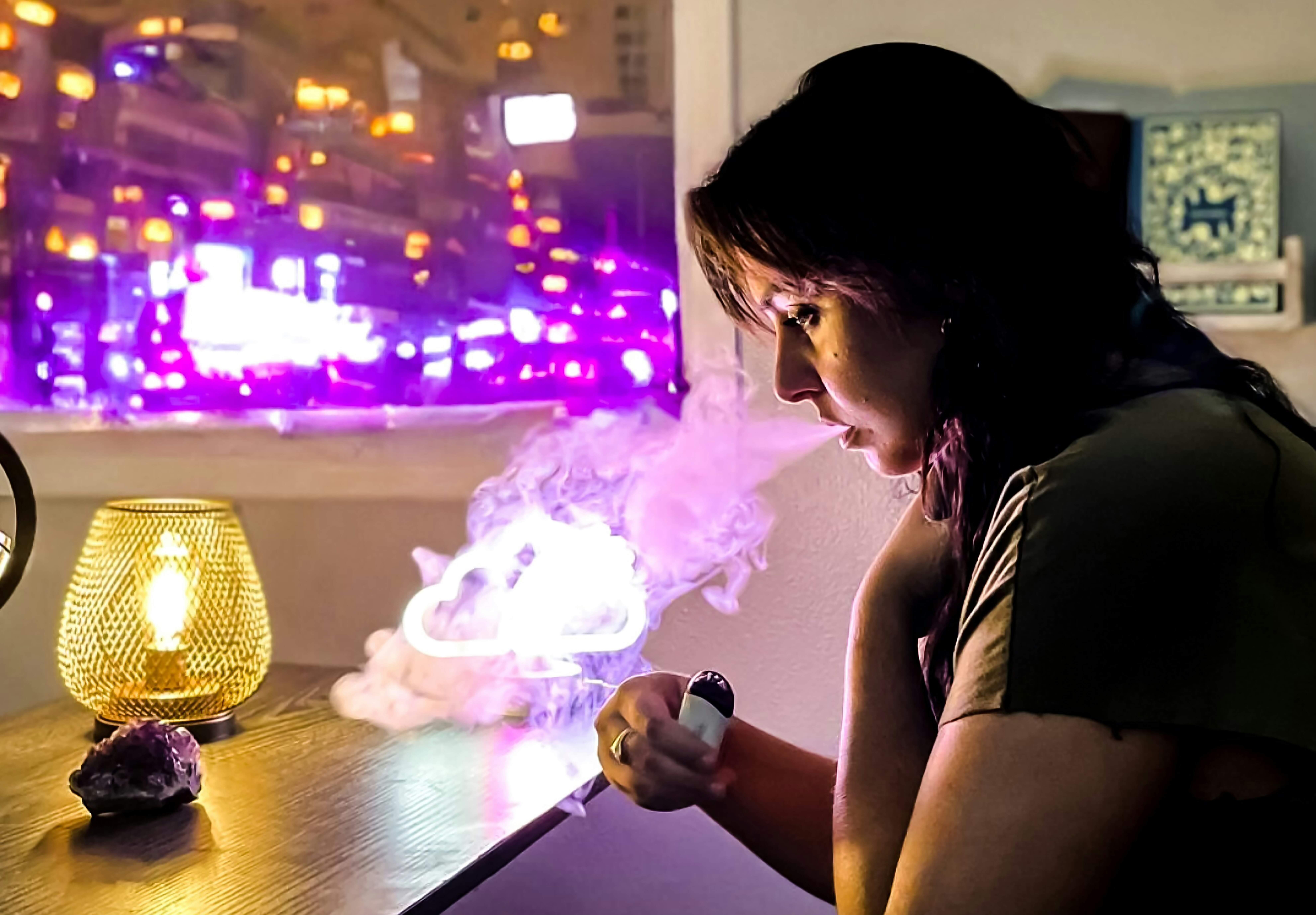 A woman sitting at a table and using a vaporizer