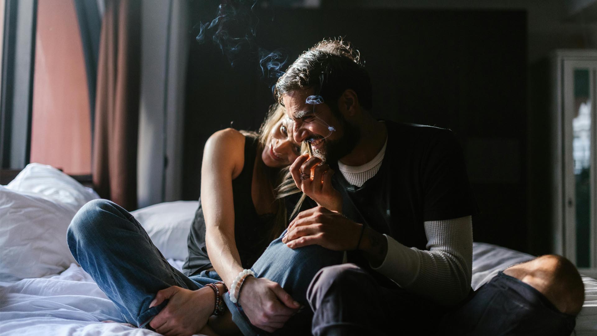 Man and woman smoking cannabis in bed