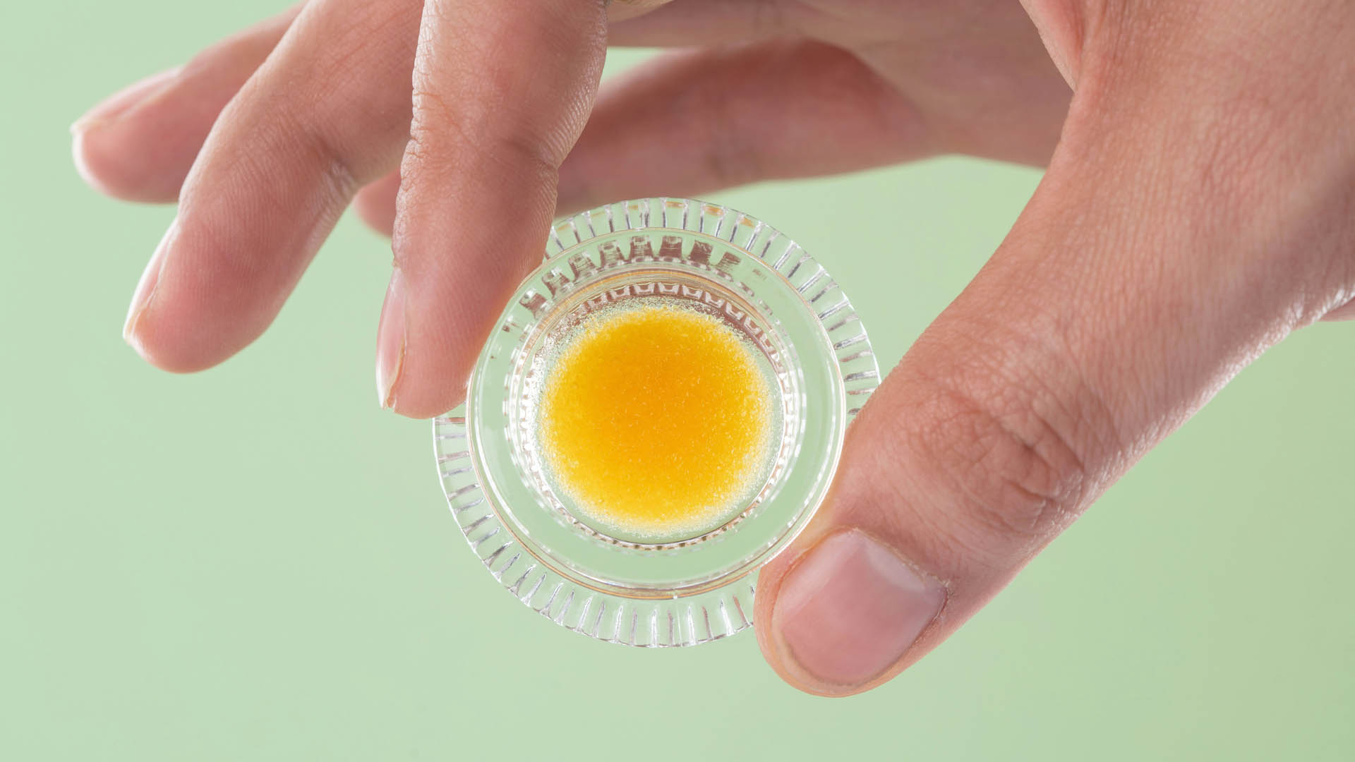 Hand holding cannabis extract in a glass jar