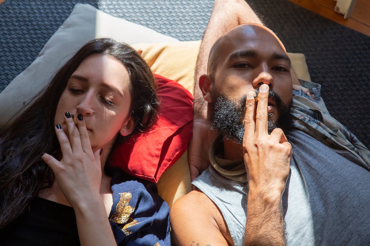 A man and a woman lying on the floor and smoking weed