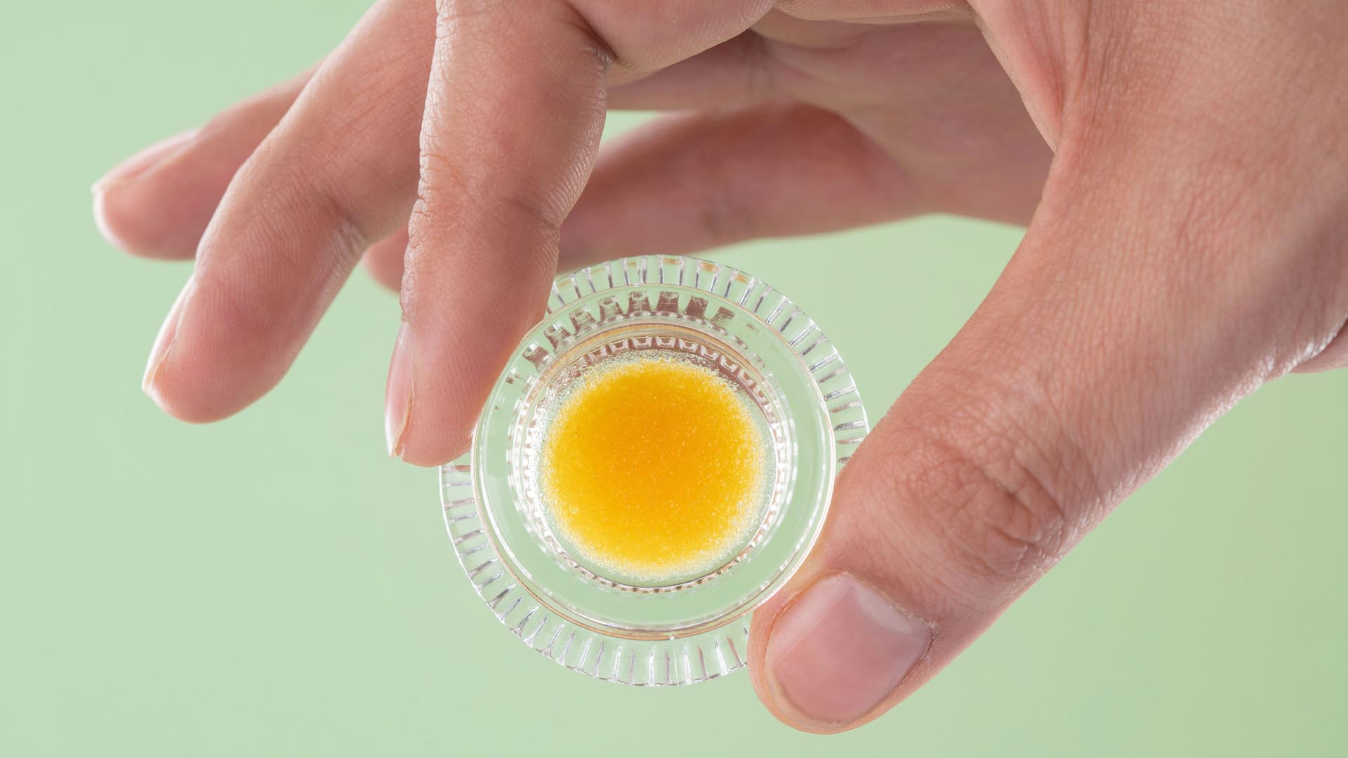 Hand holding a jar of cannabis concentrate