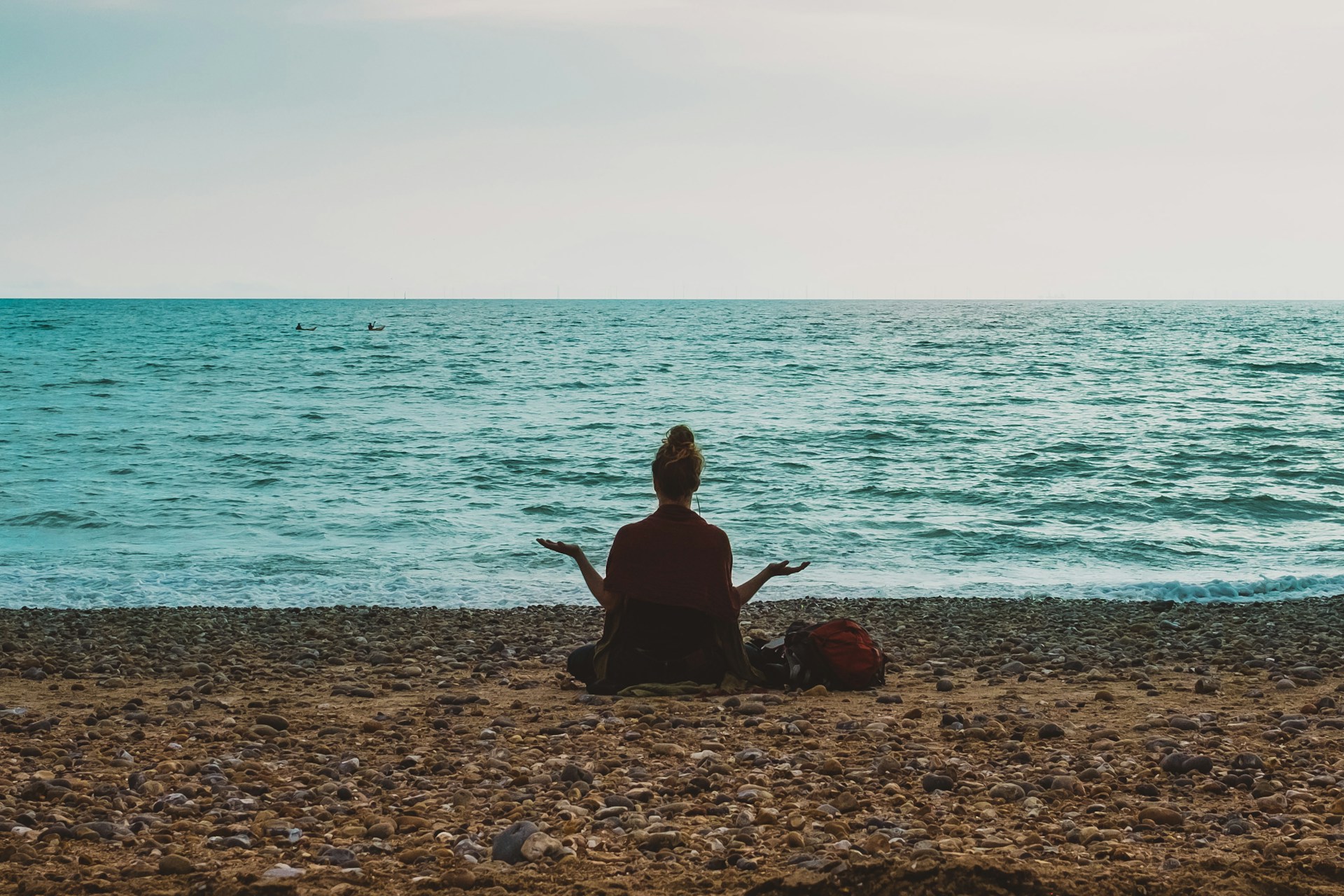 Woman meditating on a beach at sunset