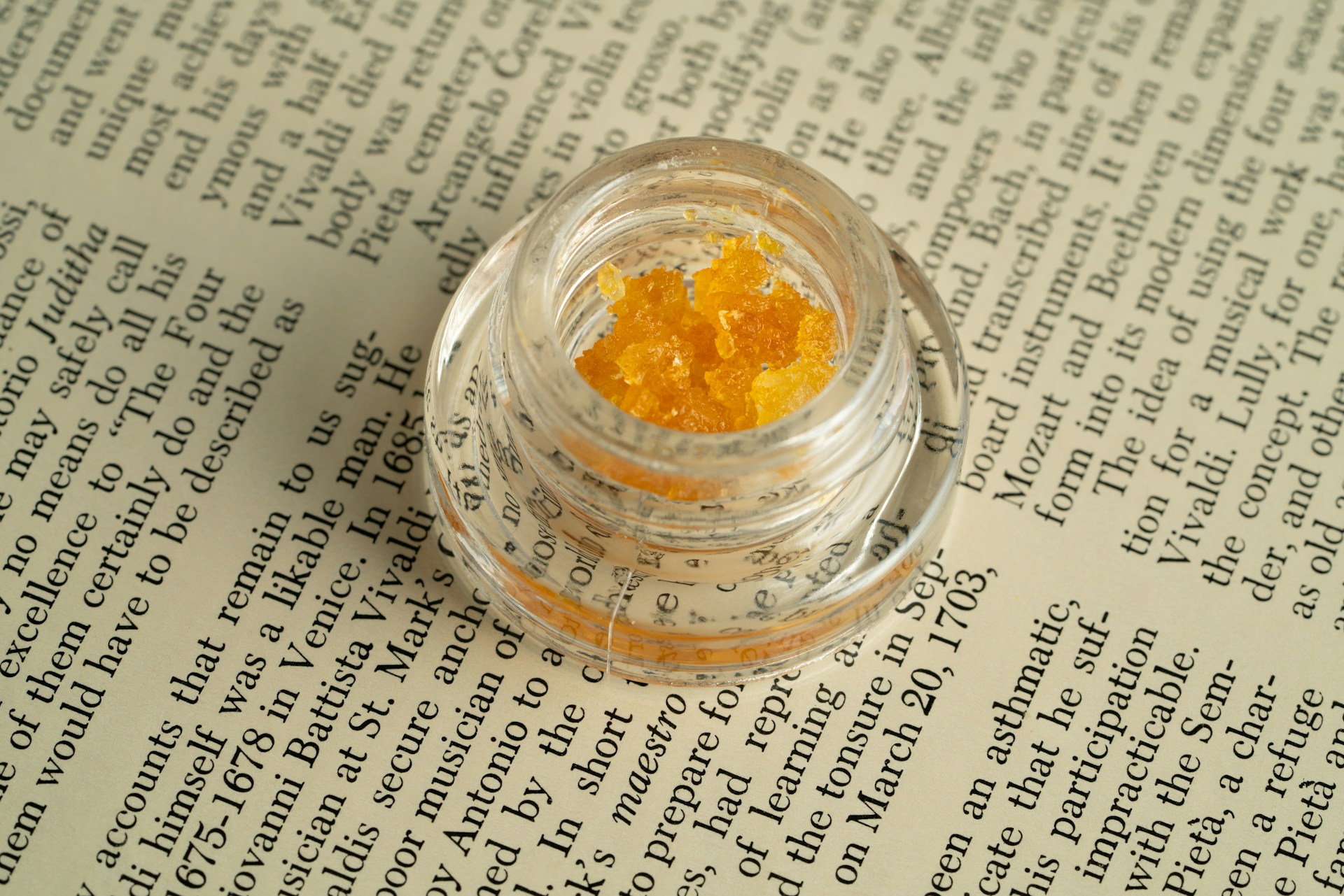 Glass jar of cannabis resin sitting on a page of a book